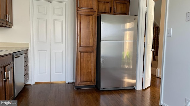 kitchen with appliances with stainless steel finishes, dark wood-type flooring, light countertops, and brown cabinets