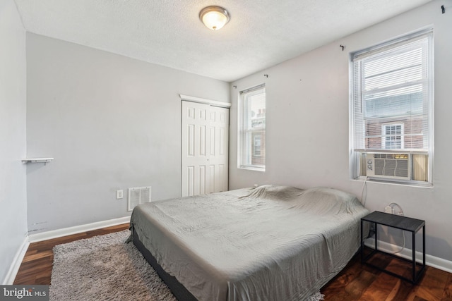 bedroom featuring multiple windows, wood finished floors, a closet, and baseboards