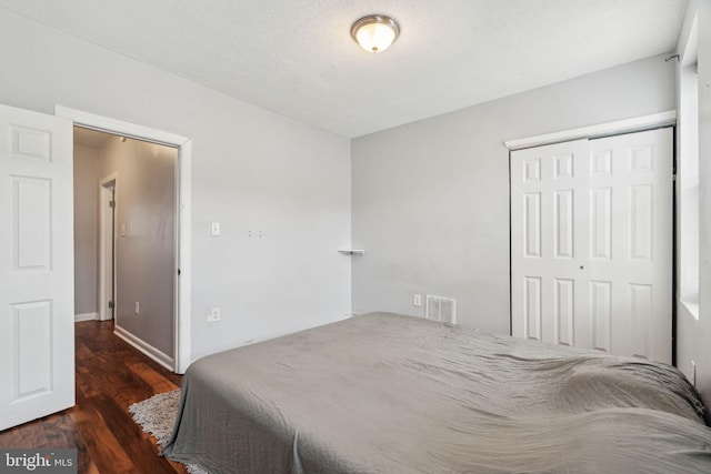 bedroom with visible vents, wood finished floors, and a closet