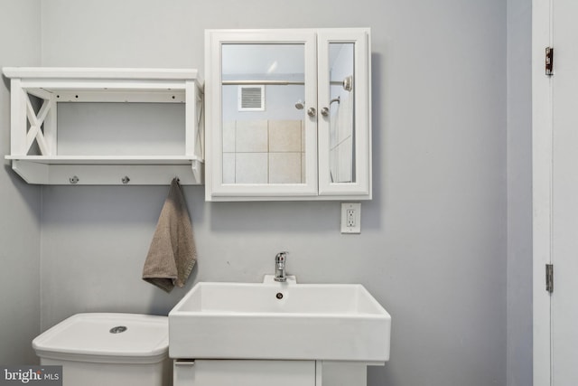 bathroom featuring a sink, toilet, and visible vents