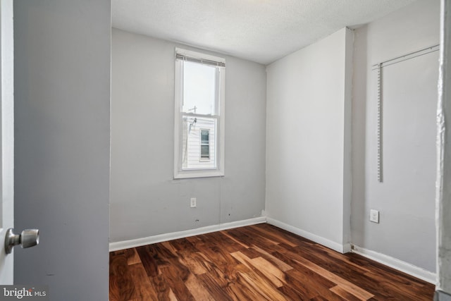 unfurnished room featuring baseboards, a textured ceiling, and dark wood-style flooring
