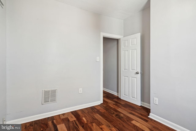 empty room with visible vents, baseboards, and dark wood-type flooring