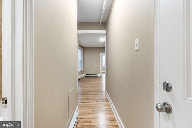 hall with light wood-style flooring, baseboards, baseboard heating, and attic access
