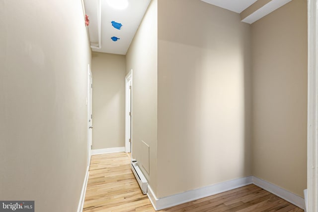 hallway with baseboards, baseboard heating, and light wood-type flooring