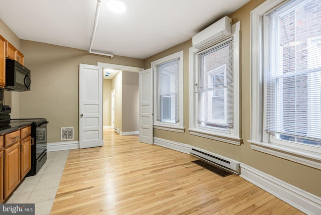 kitchen with an AC wall unit, brown cabinets, black appliances, and visible vents