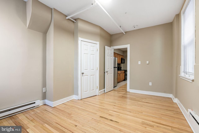 spare room featuring baseboards, light wood-style flooring, and baseboard heating