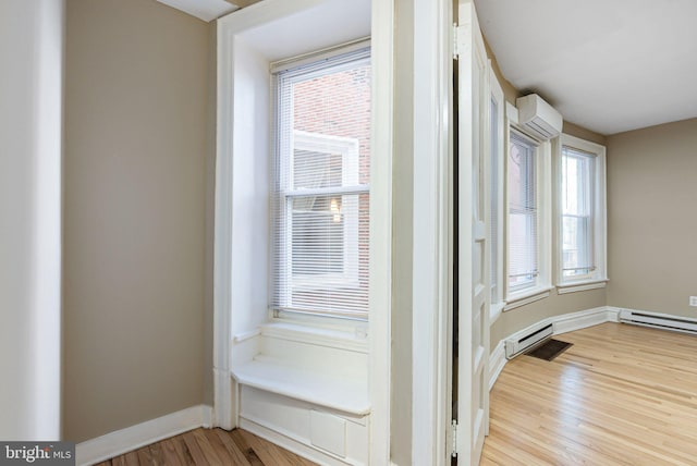 interior space featuring baseboards, a wall mounted AC, baseboard heating, and light wood-type flooring