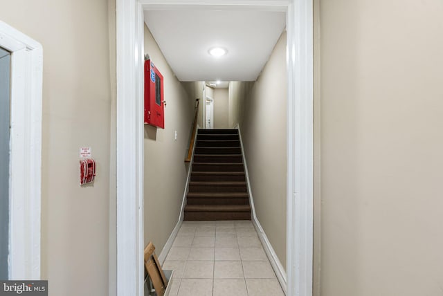 hallway featuring stairs, baseboards, and light tile patterned floors