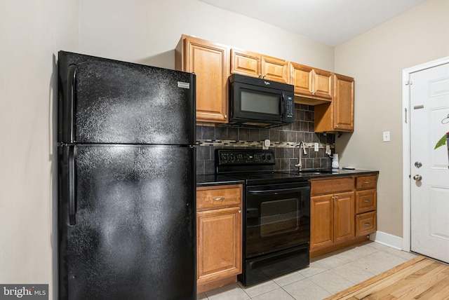 kitchen with a sink, dark countertops, tasteful backsplash, and black appliances