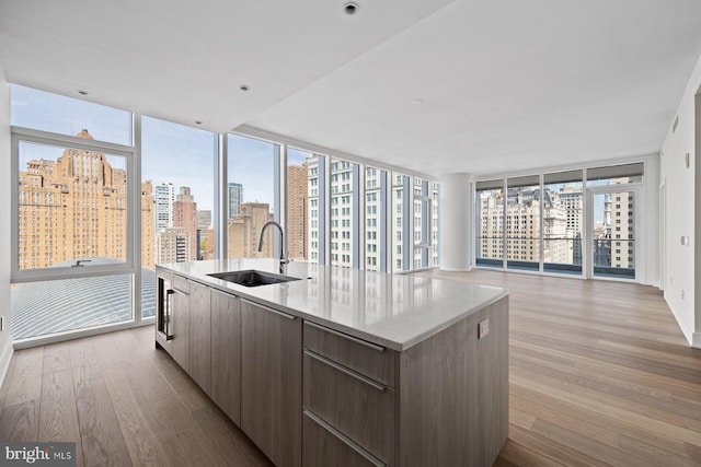 301 S Broad St Unit 1901-2, Philadelphia, PA 19107 - kitchen featuring modern cabinets, a sink, a kitchen island with sink, light wood-style flooring, and a view of city