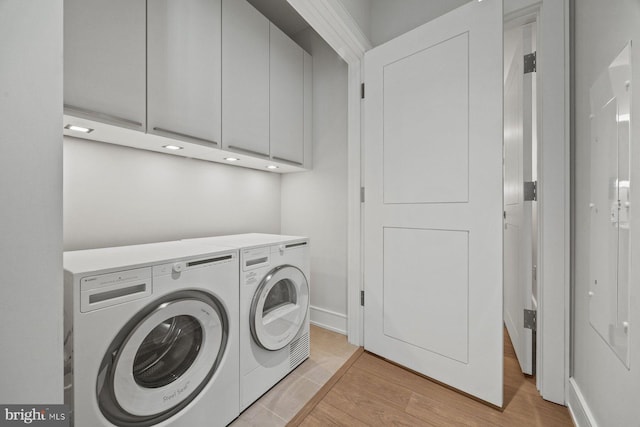 301 S Broad St Unit 1901-2, Philadelphia, PA 19107 - laundry area featuring baseboards, cabinet space, washer and clothes dryer, and light wood-type flooring