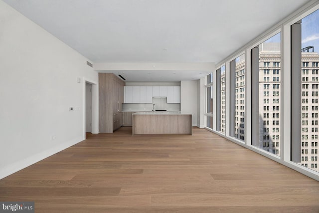 301 S Broad St Unit 1901-2, Philadelphia, PA 19107 - unfurnished living room with light wood-style floors, visible vents, baseboards, and a sink
