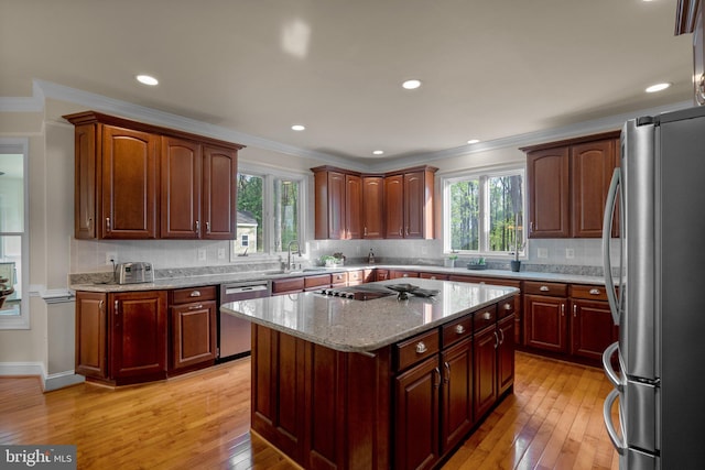 kitchen with plenty of natural light, stainless steel appliances, light wood-type flooring, and ornamental molding