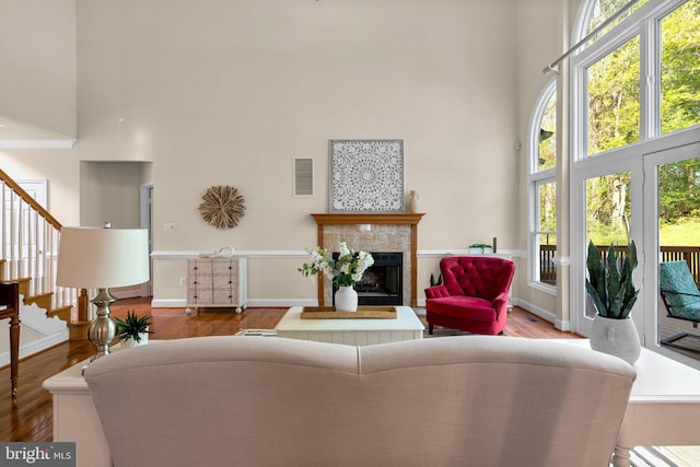 living room with a tiled fireplace, visible vents, stairs, and a towering ceiling
