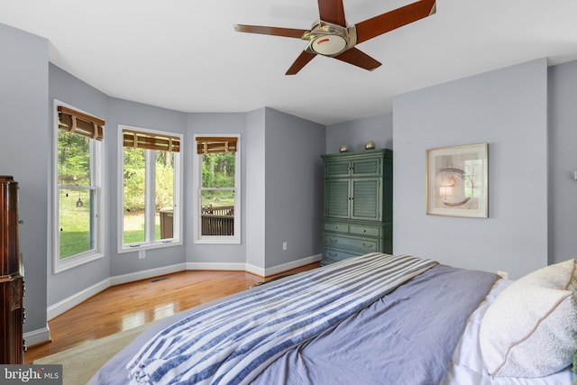 bedroom featuring baseboards, light wood-type flooring, and multiple windows