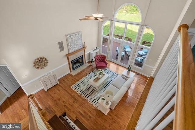 living area featuring baseboards, visible vents, wood finished floors, and a tile fireplace