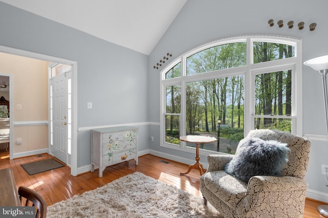 living area featuring baseboards, hardwood / wood-style flooring, and lofted ceiling
