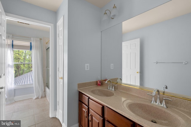 full bathroom with double vanity, tile patterned floors, baseboards, and a sink