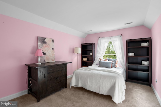 bedroom with lofted ceiling, light colored carpet, visible vents, and baseboards