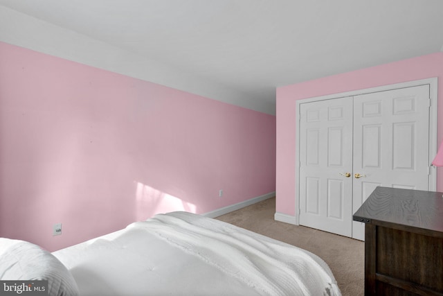 bedroom featuring baseboards, light carpet, and a closet