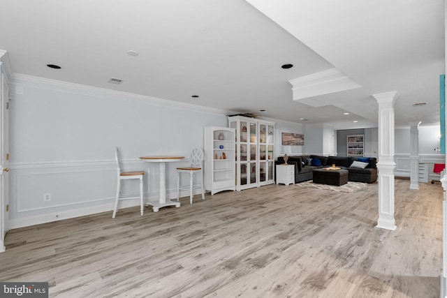 interior space with crown molding, wood finished floors, and ornate columns