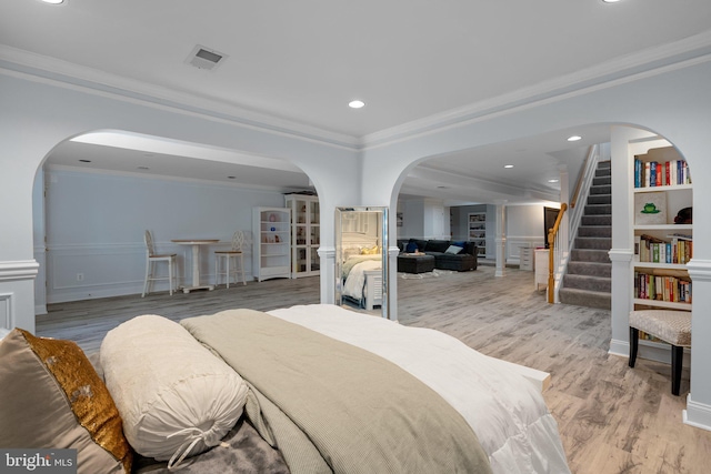 bedroom with visible vents, light wood-style floors, arched walkways, recessed lighting, and ornamental molding