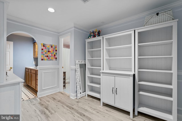 walk in closet featuring arched walkways and light wood finished floors