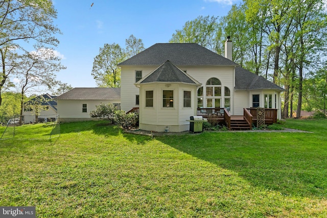 back of property with a chimney, a deck, and a yard