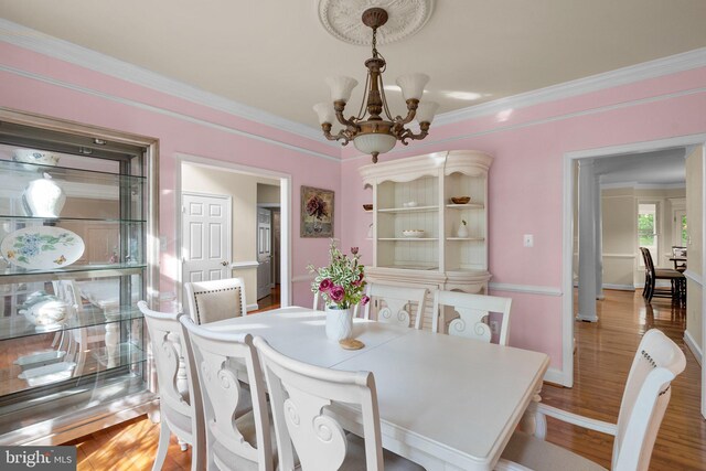 dining room featuring ornamental molding, an inviting chandelier, wood finished floors, and baseboards