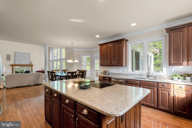 kitchen with a sink, a kitchen island, black electric stovetop, and plenty of natural light