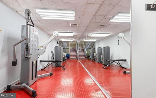 gym with a drop ceiling, visible vents, and baseboards