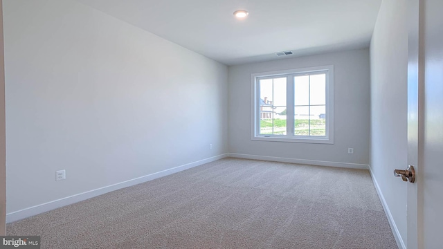 unfurnished room with baseboards, visible vents, and light carpet