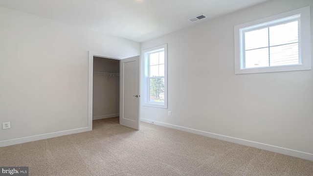 unfurnished bedroom with baseboards, carpet flooring, visible vents, and a closet