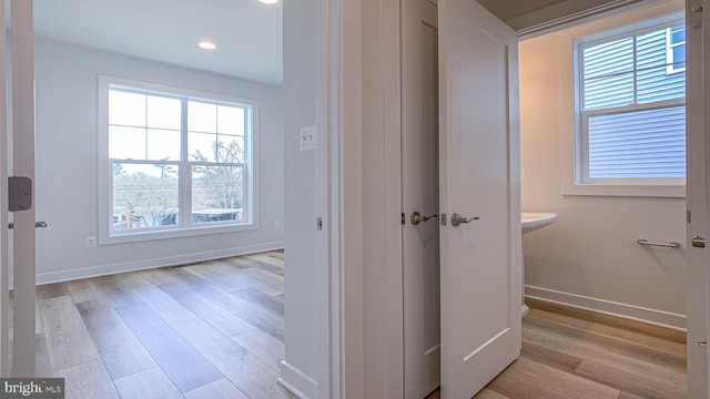 hallway with baseboards, recessed lighting, and light wood-style flooring