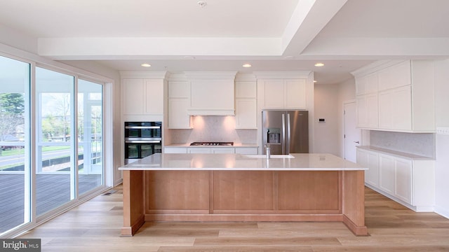 kitchen with a sink, light wood finished floors, tasteful backsplash, and stainless steel appliances