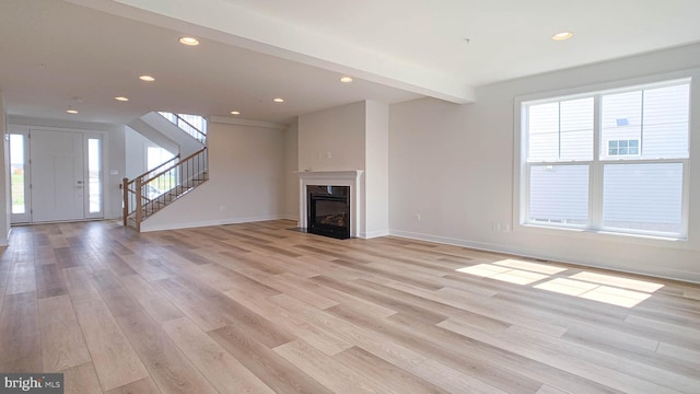 unfurnished living room with stairs, recessed lighting, baseboards, and light wood-style flooring