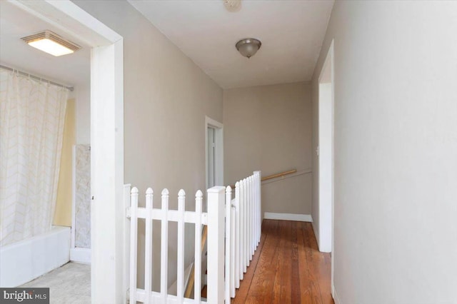 corridor featuring baseboards and wood finished floors