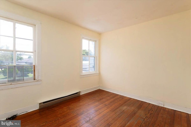 spare room with baseboards, a baseboard radiator, and dark wood finished floors