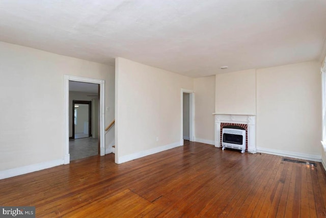 unfurnished living room featuring stairway, heating unit, wood-type flooring, baseboards, and a fireplace