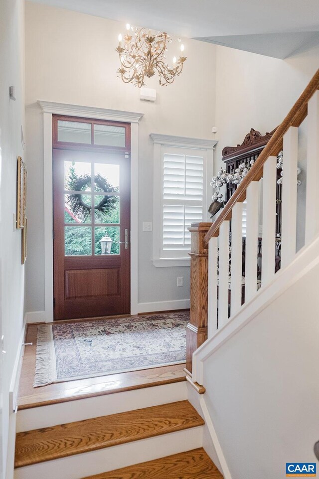 entryway with a chandelier, stairs, and baseboards