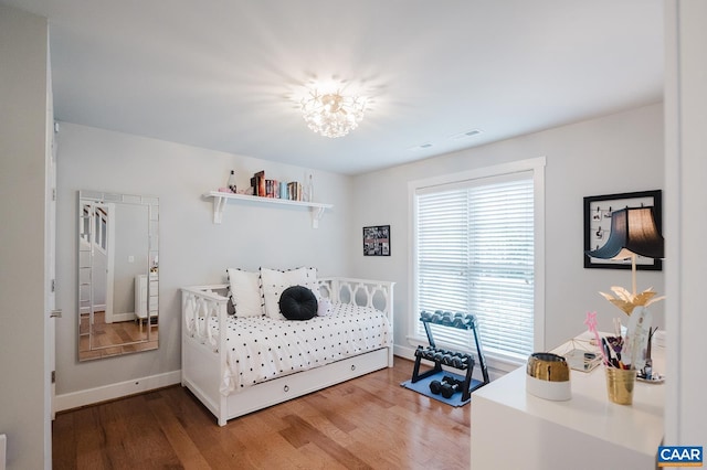 bedroom featuring baseboards, a notable chandelier, and wood finished floors