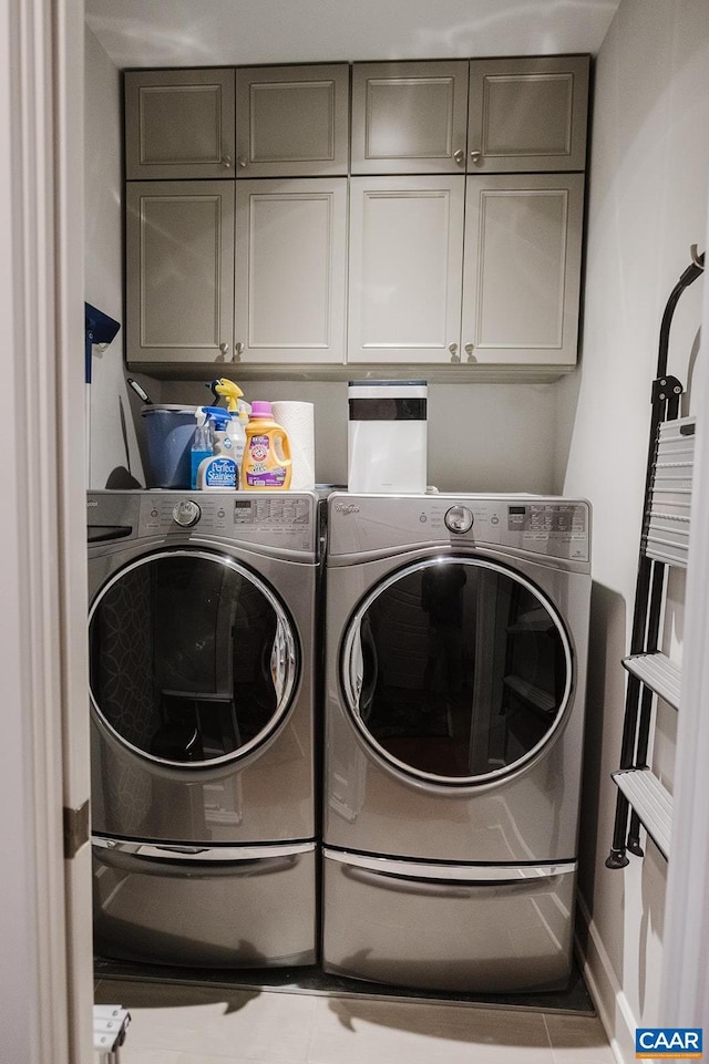 washroom with cabinet space, baseboards, and washer and dryer