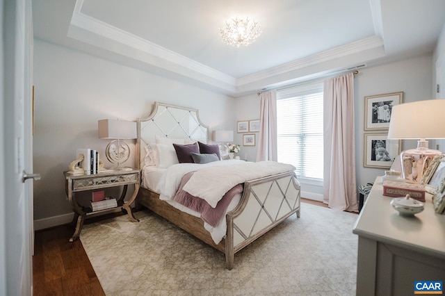 bedroom featuring light wood finished floors, an inviting chandelier, a tray ceiling, crown molding, and baseboards