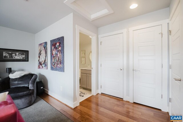 living area with attic access, light wood-style flooring, and baseboards