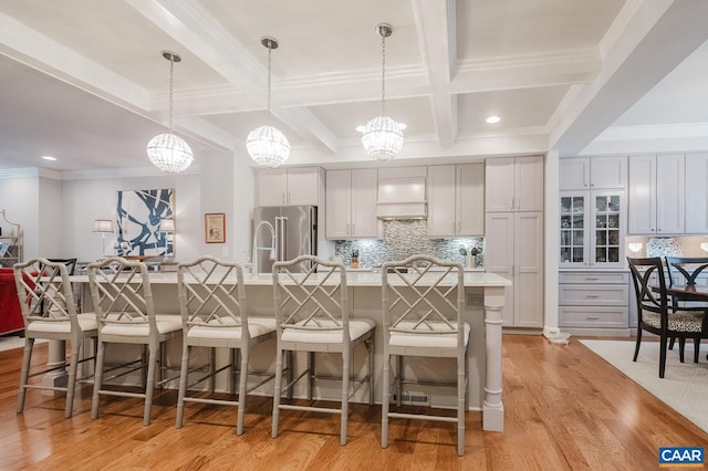 kitchen with high end refrigerator, a notable chandelier, a large island with sink, and a breakfast bar area