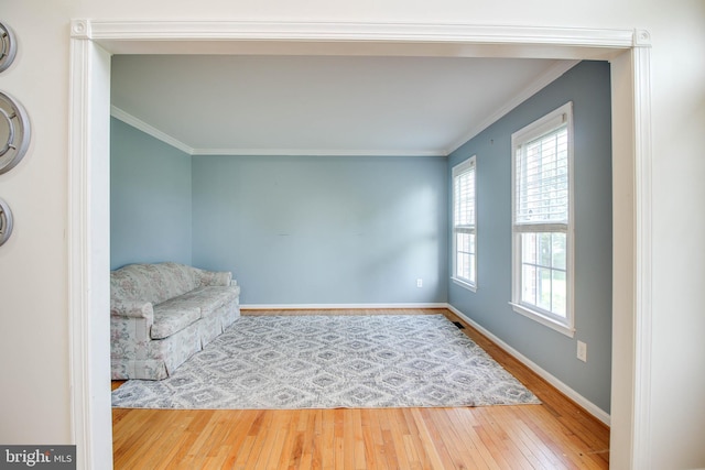living area featuring wood-type flooring, crown molding, and baseboards