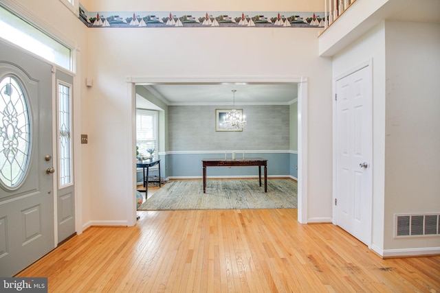 foyer featuring light wood-style floors, baseboards, an inviting chandelier, and visible vents