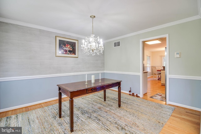dining area with a notable chandelier, baseboards, wood finished floors, visible vents, and ornamental molding