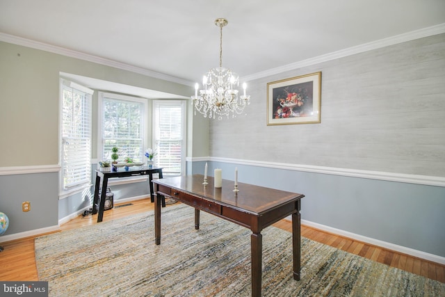 dining area featuring baseboards, a notable chandelier, ornamental molding, and wood finished floors