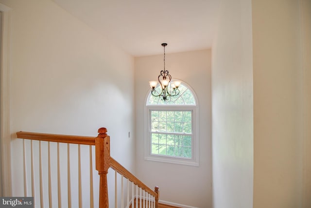 staircase featuring an inviting chandelier and baseboards